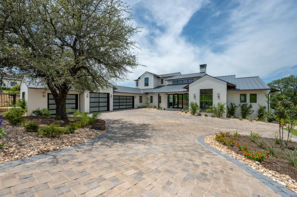 White modern farmhouse with a dark standing-seam metal roof and motor court
